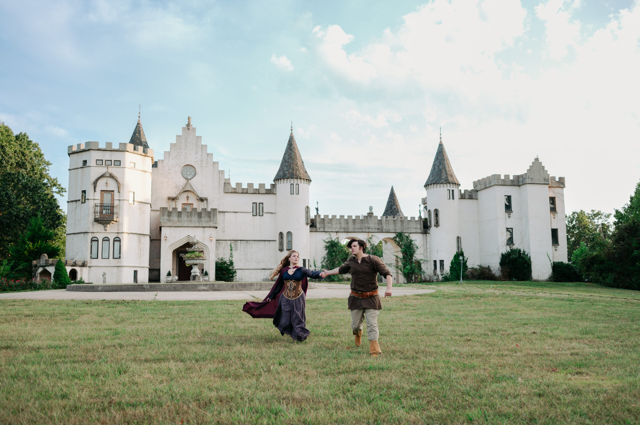 Man and woman in Renaissance outfits posing in front of a white castle venue